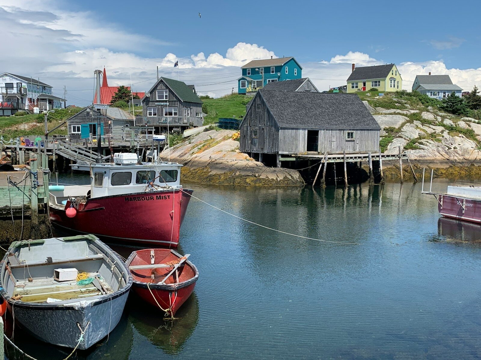 red and white boat on water near brown wooden house during daytime