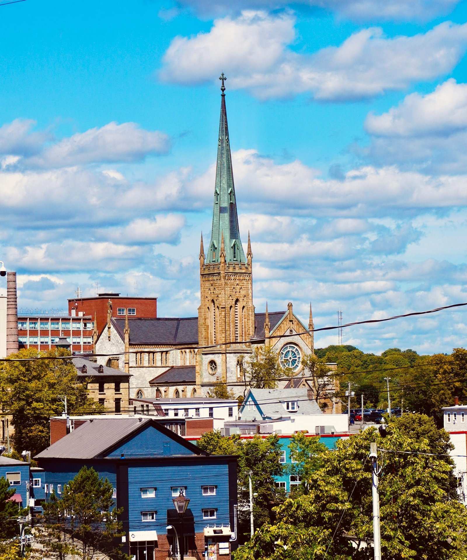 A vibrant cityscape featuring a historic cathedral spire and colorful buildings under a bright blue sky.