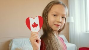 Adorable child holding a heart-shaped Canadian flag, symbolizing patriotism and innocence.